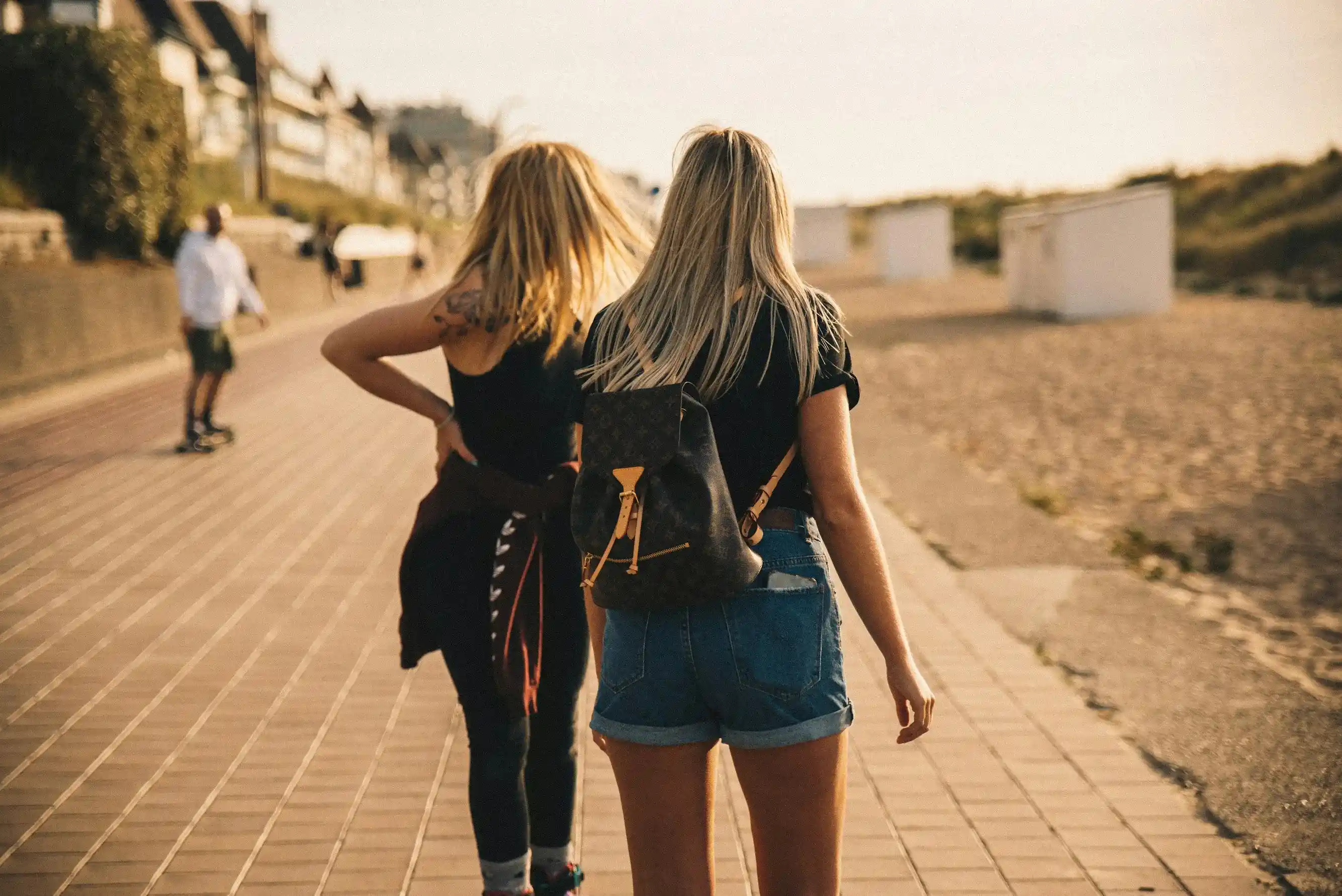 Two friends walking along a sunny boardwalk